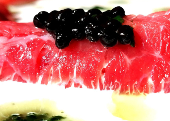 Rotllets de carpaccio de vedella amb crema agra, perles de trufa negra i oli de ruca