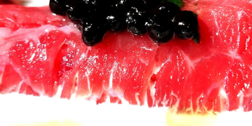 Rotllets de carpaccio de vedella amb crema agra, perles de trufa negra i oli de ruca