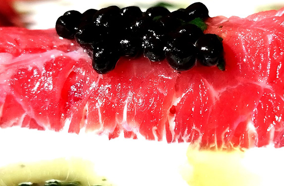 Rotllets de carpaccio de vedella amb crema agra, perles de trufa negra i oli de ruca