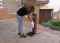 Una veïna de Prat de Comte omple garrafes d’aigua en una font del municipi