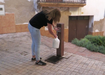 Una veïna de Prat de Comte omple garrafes d’aigua en una font del municipi